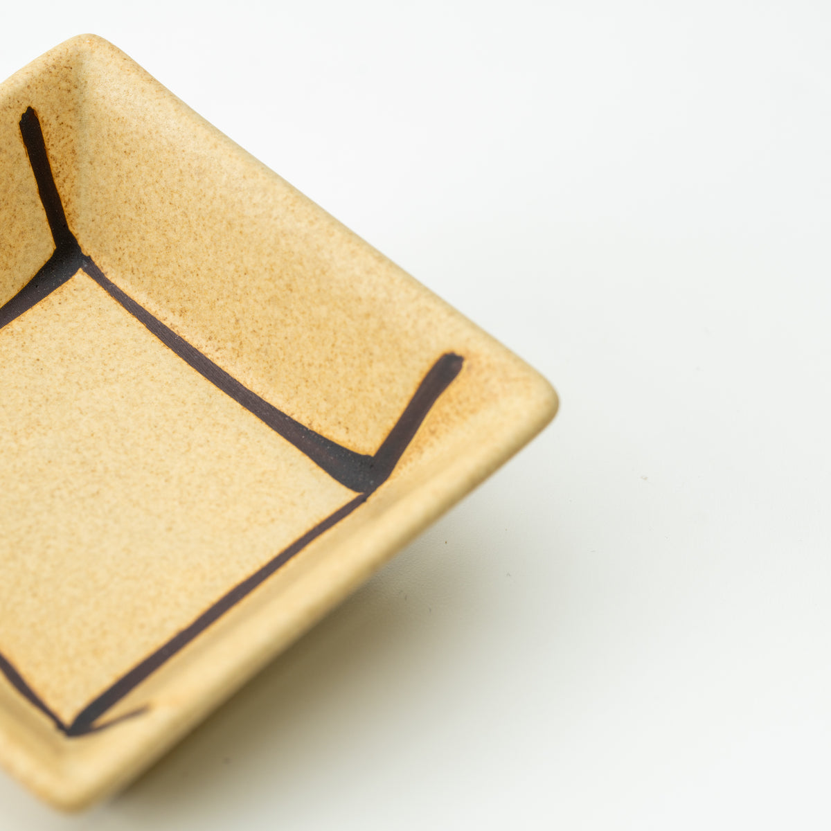 Close-up of a tan Mino bowl's speckled finish and dark outlined square pattern.