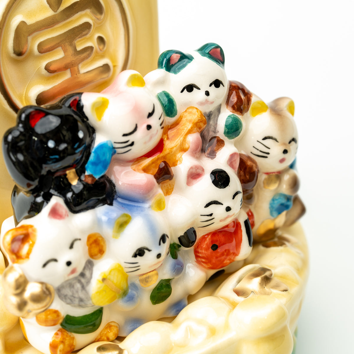 Close-up of the colorful lucky cats clustered in front of the treasure ship's gold-colored sail emblem.