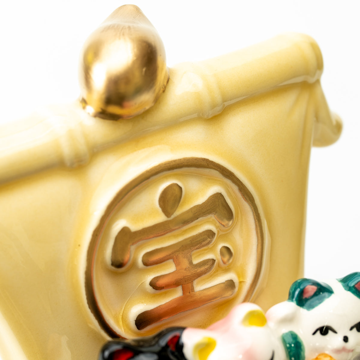 Close-up of the raised gold-colored character and rounded finial on the lucky cat treasure ship's sail.