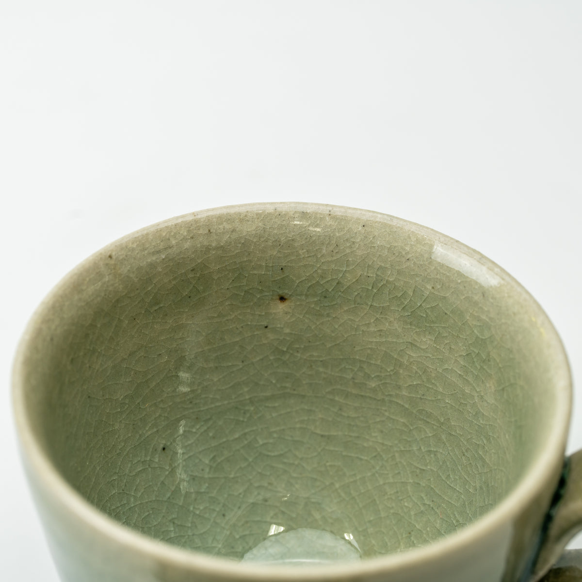 Close-up into the Hechimon Mosaic cup showing its green crackled glaze and rounded rim.