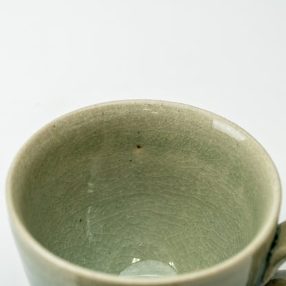 Close-up into the Hechimon Mosaic cup showing its green crackled glaze and rounded rim.