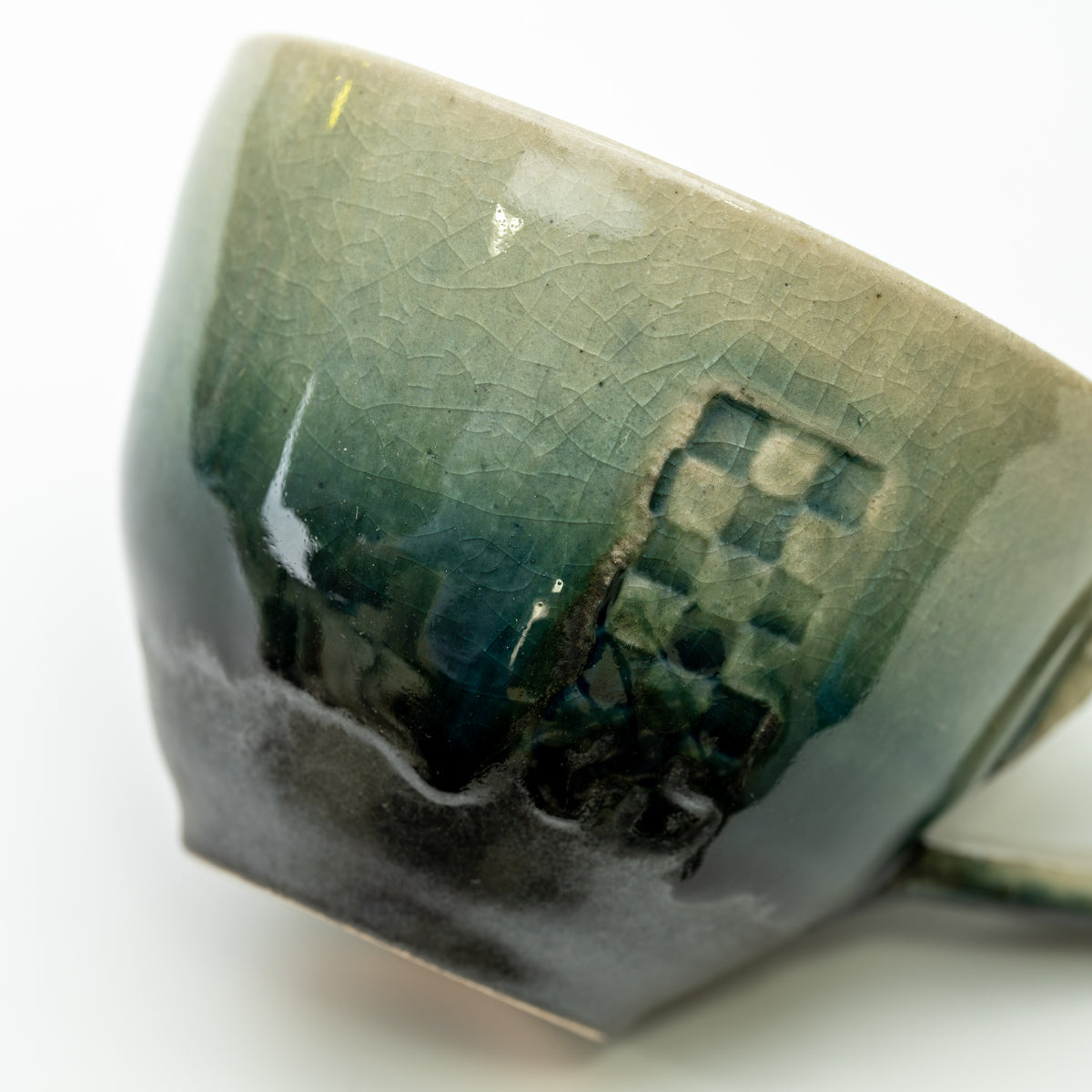Close-up of the Mosaic cup's checkered panel and the transition from pale green to dark glaze.