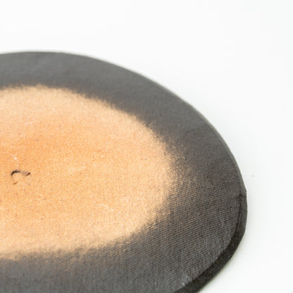 Underside detail of the Hechimon Mosaic saucer showing its tan center and dark outer edge.