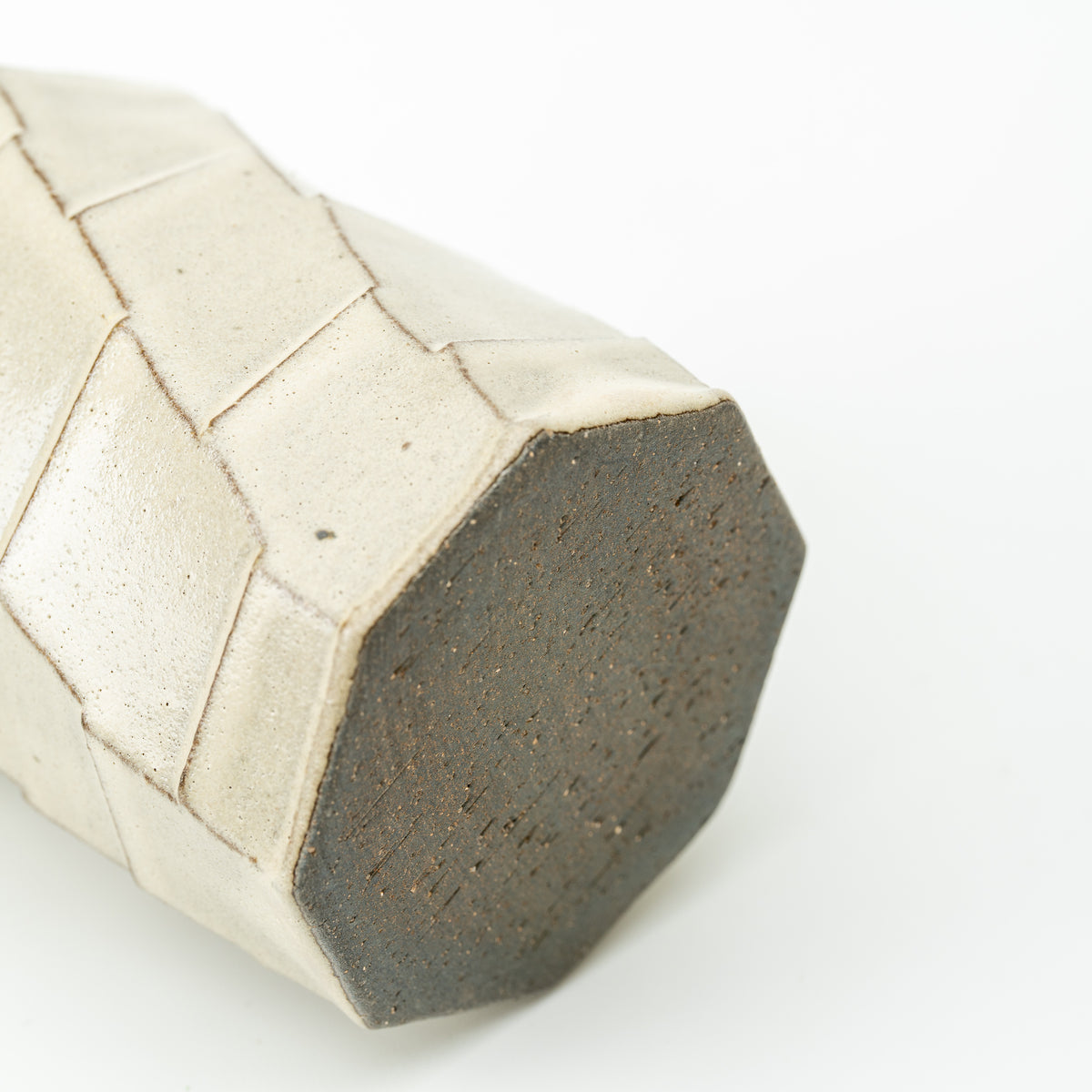 Underside of the Hechimon Greige mug showing its dark polygonal base and patterned sides.