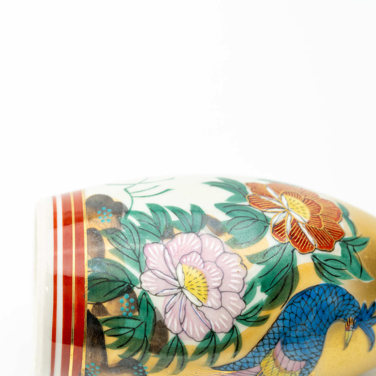 Close-up of pink and orange peonies and green leaves on the Kutani sake bottle.