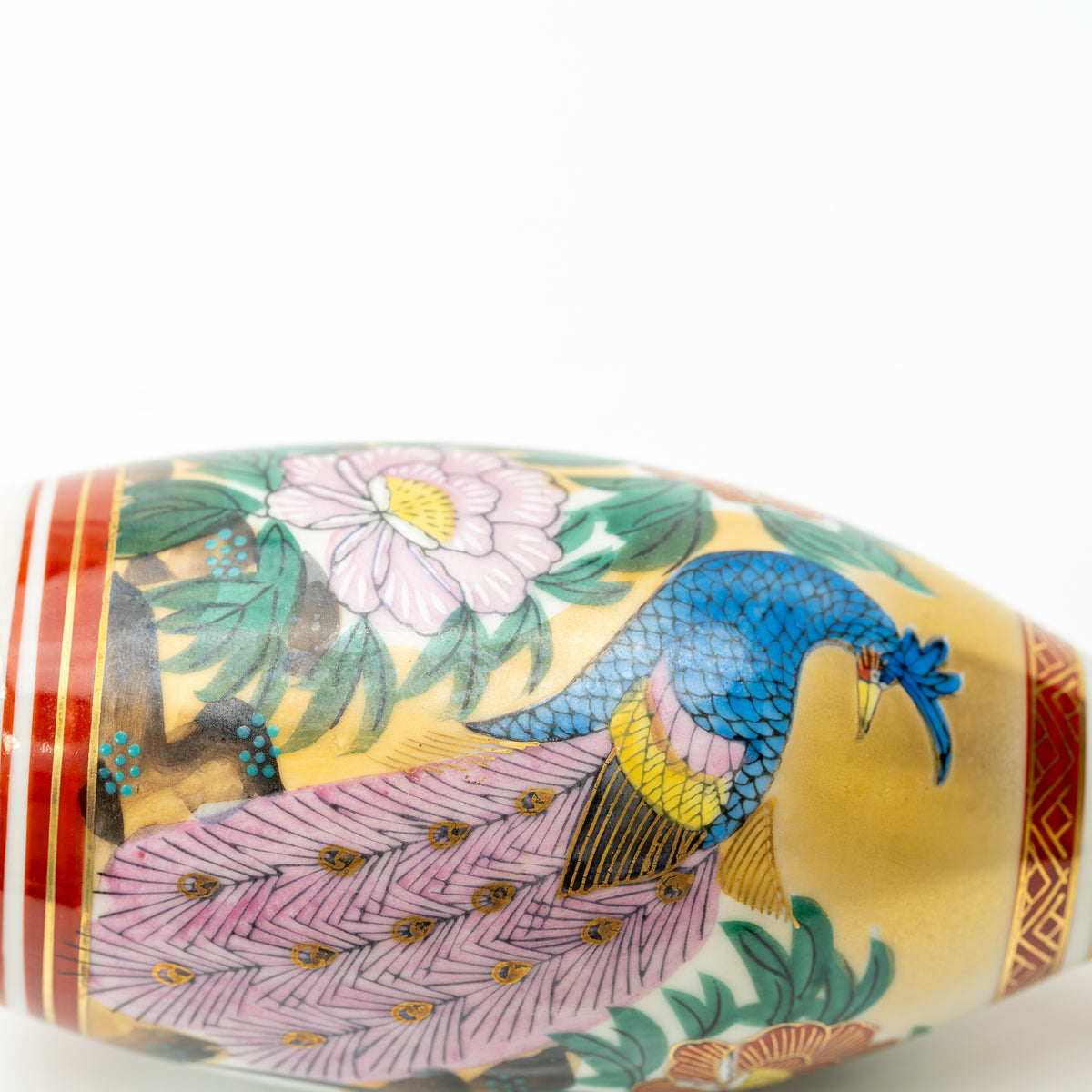 Close-up of a blue peacock with a long pink tail among peonies on the Kutani sake bottle.