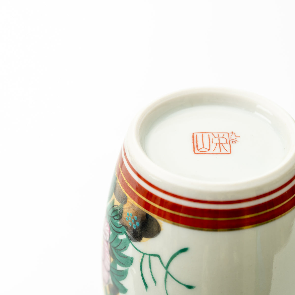 Underside detail of the Kutani sake bottle, showing its red maker's mark and striped base.