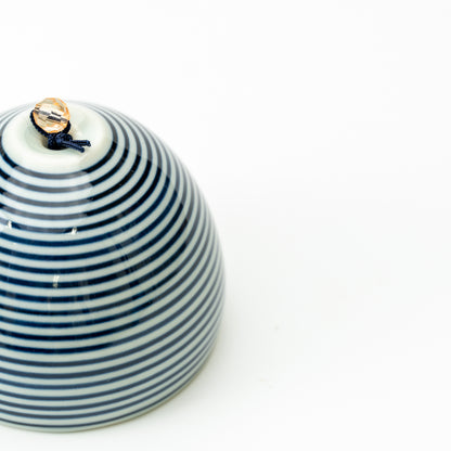 Close-up of the Arita wind-chime bell covered in fine blue-and-white horizontal stripes.