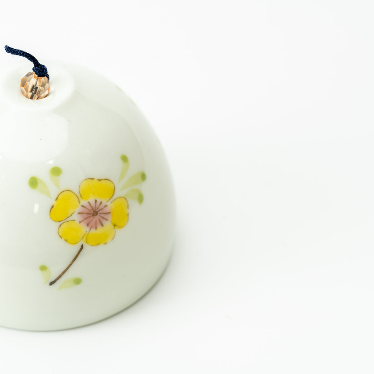 Close-up of a yellow flower with green leaves on the pale Arita wind-chime bell.