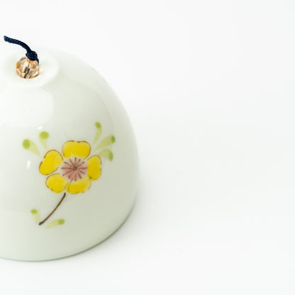 Close-up of a yellow flower with green leaves on the pale Arita wind-chime bell.
