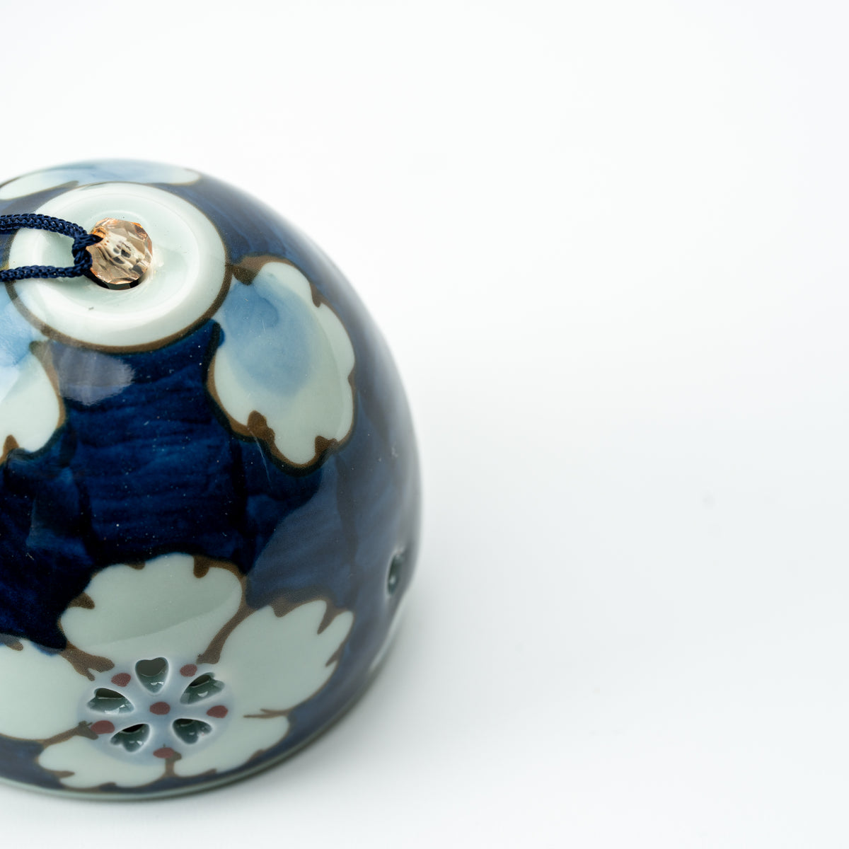 Top detail of the blue floral wind chime, showing white blossoms and the cord attachment.