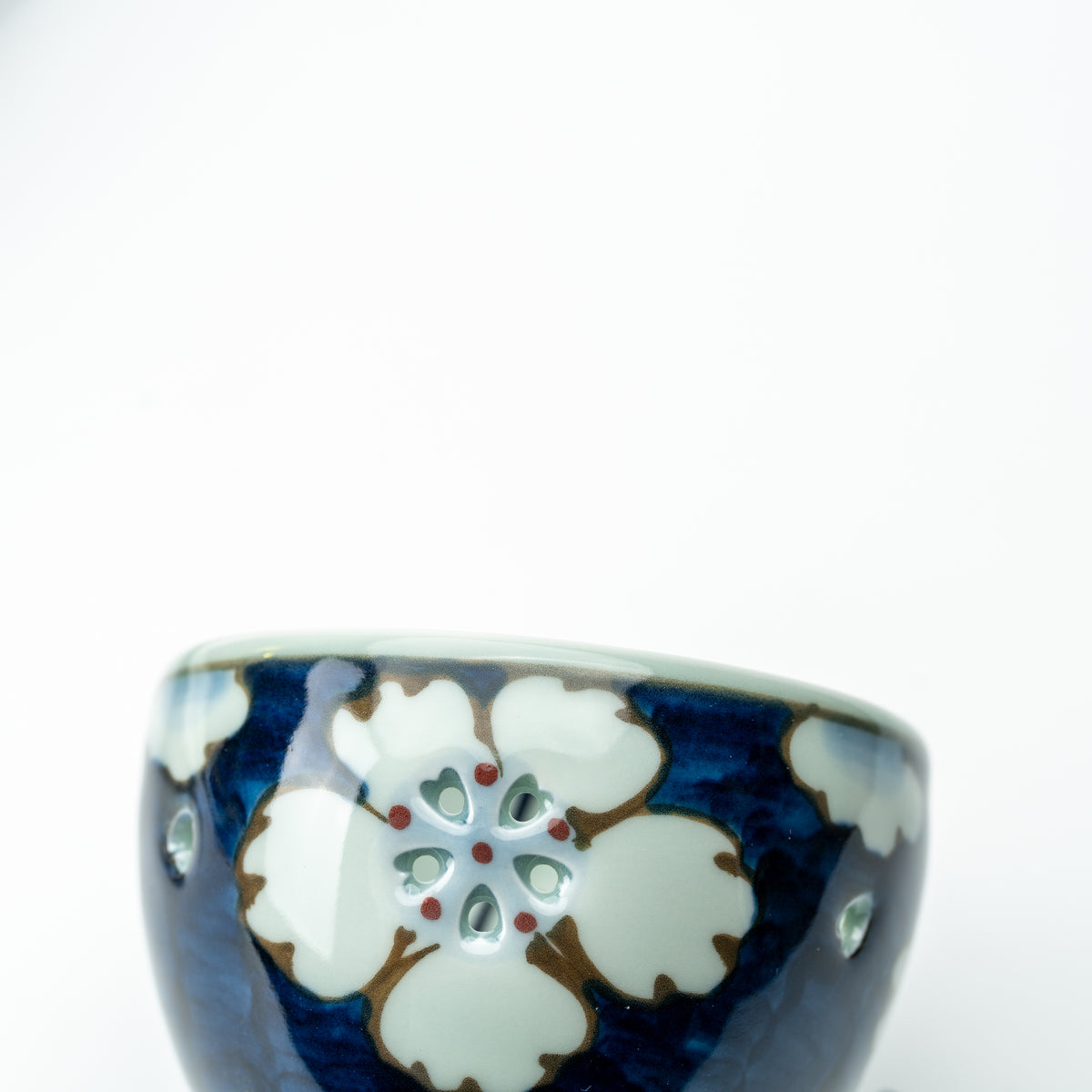 Close-up of a white flower with petal-shaped openings on the blue Arita wind-chime bell.
