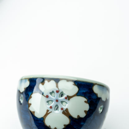 Close-up of a white flower with petal-shaped openings on the blue Arita wind-chime bell.