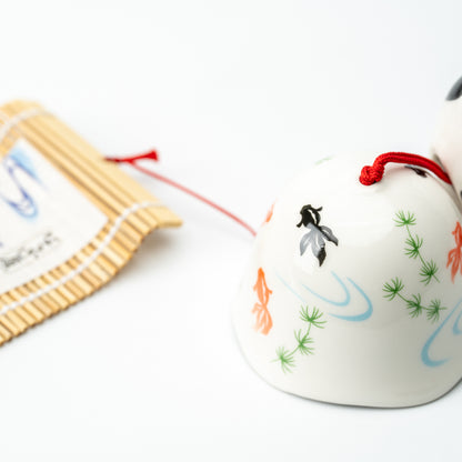 Close-up of the white wind-chime bell painted with goldfish, green plants and blue water ripples.