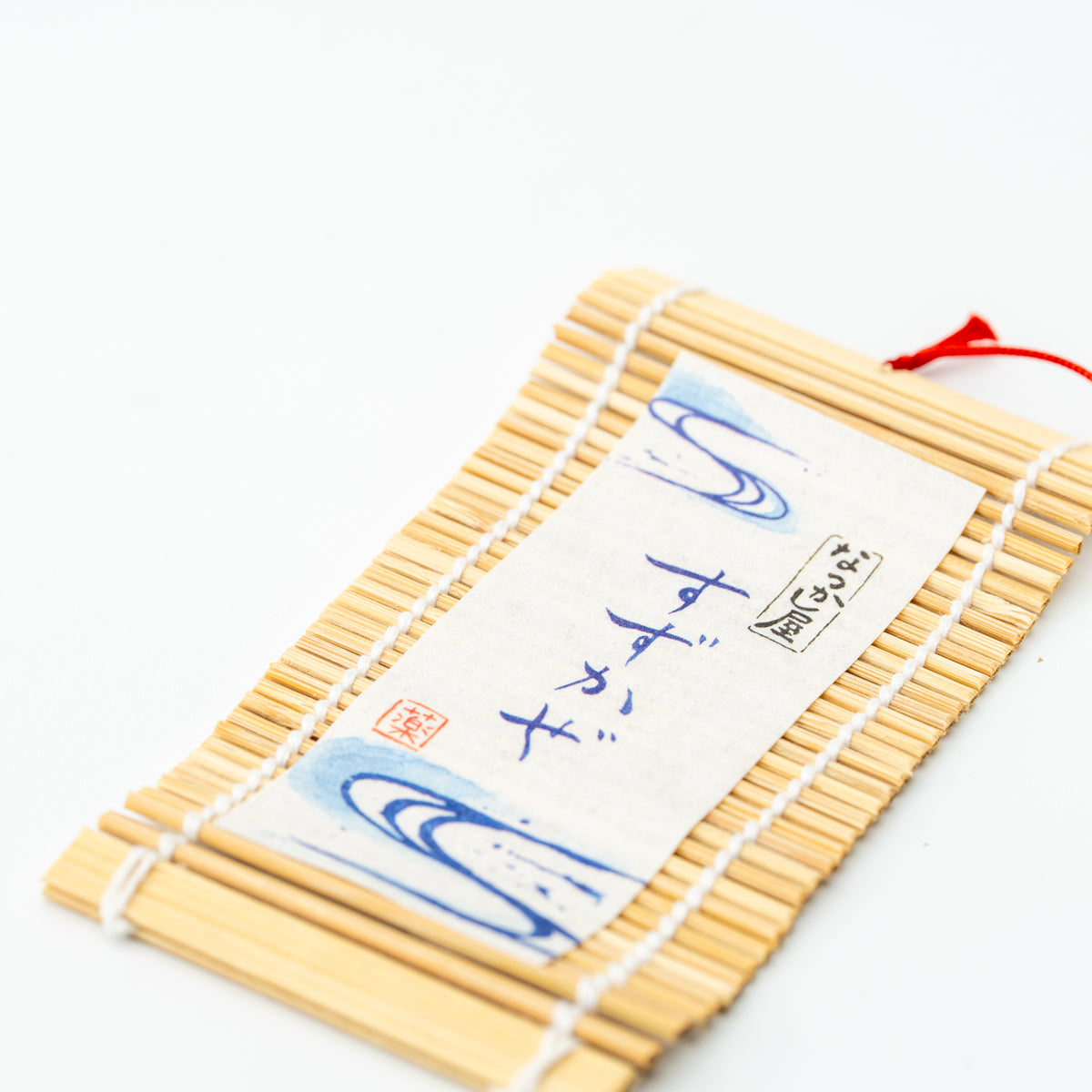 Detail of the goldfish wind chime's bamboo-backed tag with Japanese writing and blue water motifs.