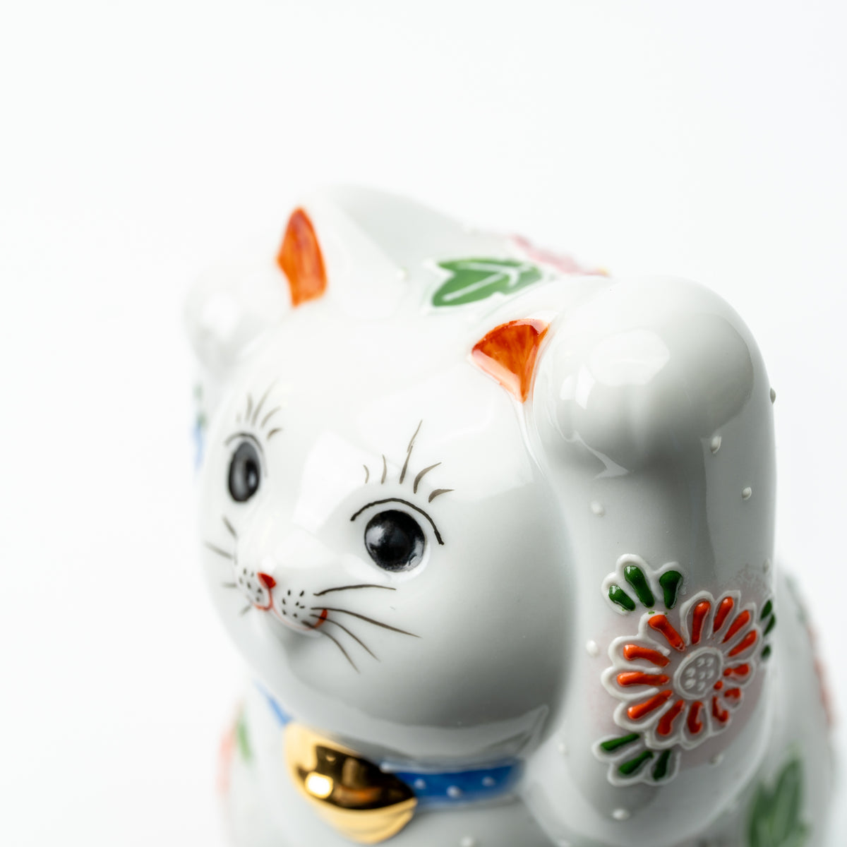 Close-up of the Hanazono lucky cat's face, raised paw and colorful floral decoration.
