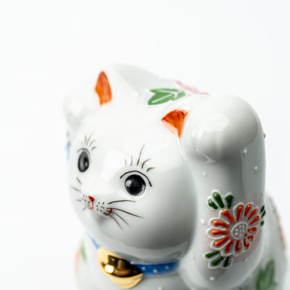 Close-up of the Hanazono lucky cat's face, raised paw and colorful floral decoration.