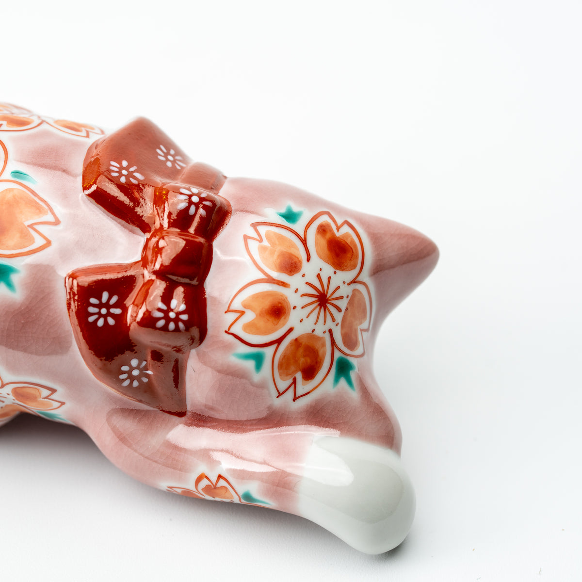Close-up of cherry blossoms and a red bow on the back of the pink Sakura lucky cat.