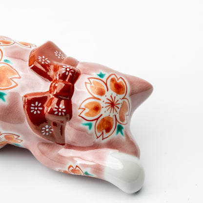 Close-up of cherry blossoms and a red bow on the back of the pink Sakura lucky cat.
