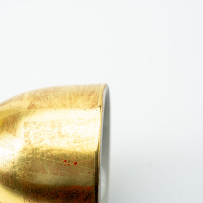 Close-up of the Kutani wine cup's gold leaf surface beside its pale rim.