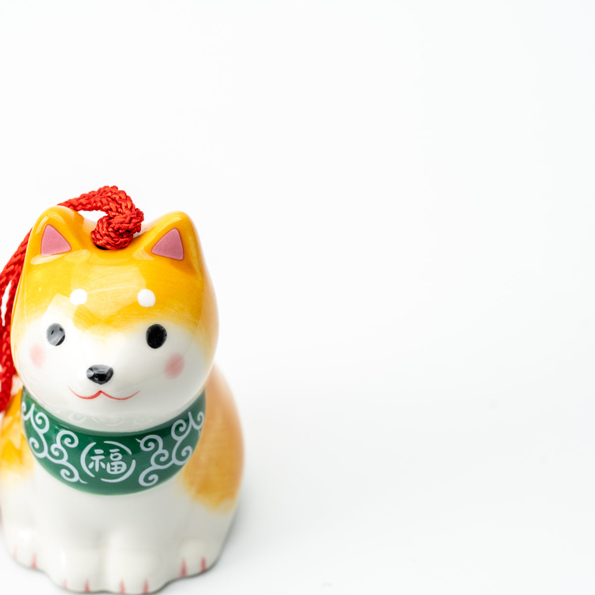 Front detail of the yellow Shiba wind chime with pink cheeks, a green bib and white paws.