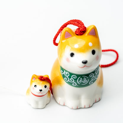 Close-up of the yellow Shiba parent and puppy, showing the parent's green patterned bib and red hanging cord.