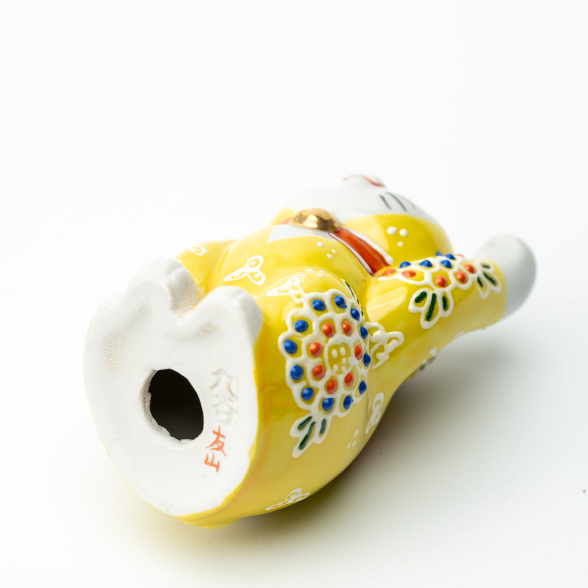 Underside of the yellow Mori lucky cat showing the base opening and red markings.