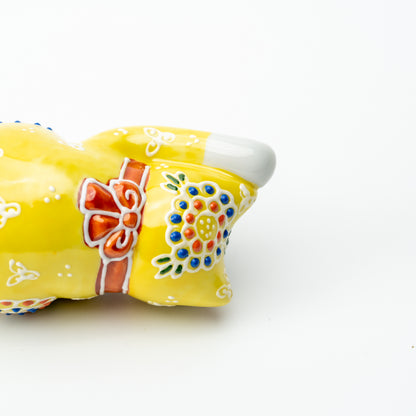 Detail of the red bow and colorful raised flower on the back of the yellow Mori lucky cat.