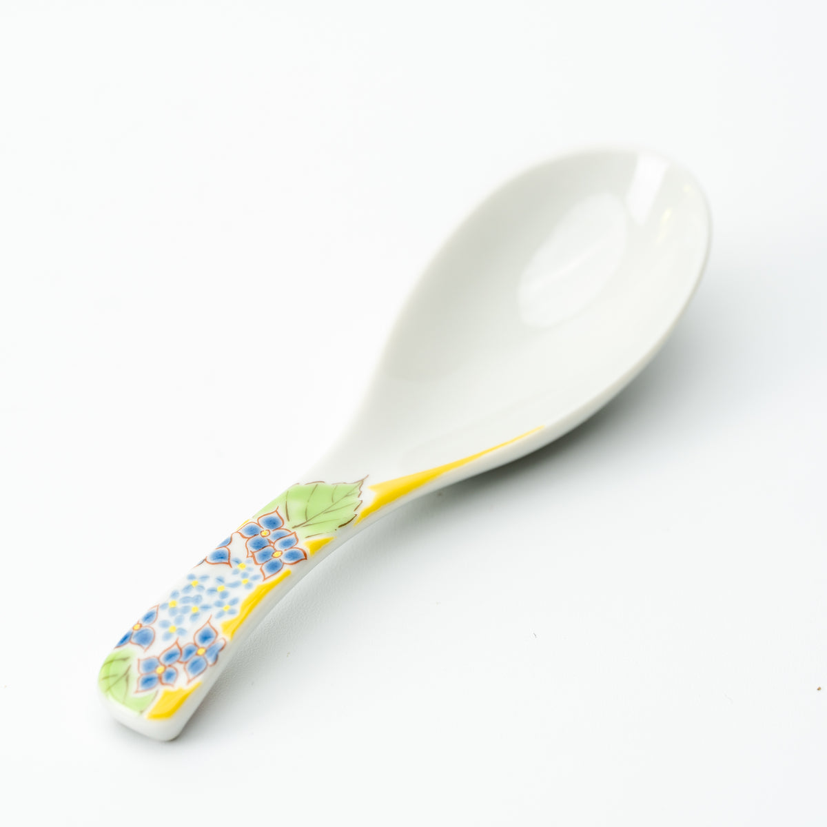 White Kutani soup spoon with blue flower clusters, green leaves and a yellow accent on the handle.