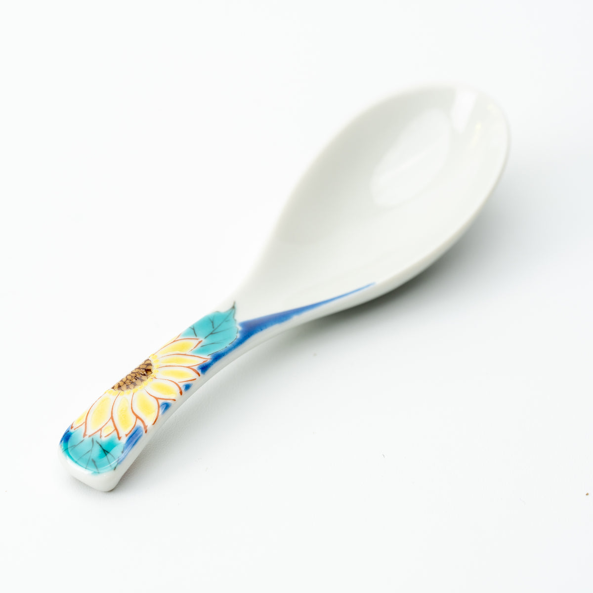 White Kutani soup spoon with a yellow sunflower and green leaves on a blue handle.