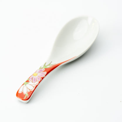 White Kutani soup spoon with pink and white flowers on a red handle.