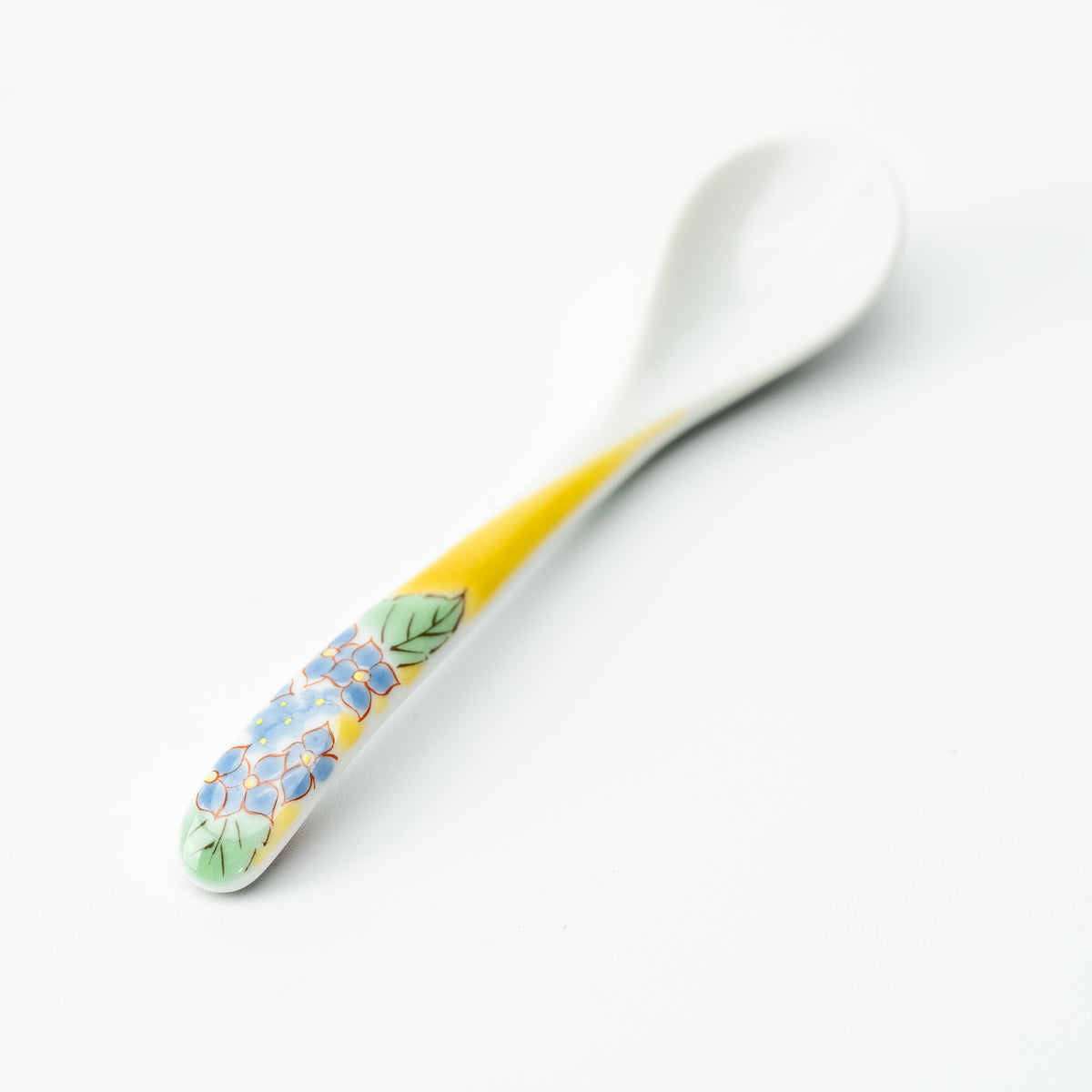 Kutani tea spoon with blue flowers and green leaves on a yellow handle.