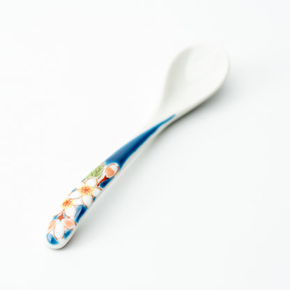 Kutani tea spoon with white blossoms and orange accents on a blue handle.