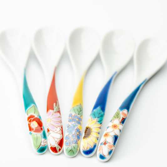 Five Kutani tea spoons fanned out to show their colorful floral handles and white bowls.