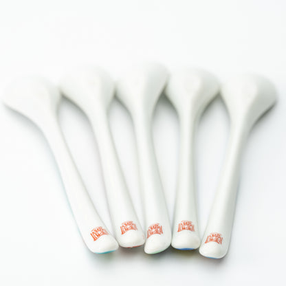 Undersides of five Kutani tea spoons showing white backs and small red marks near the handle ends.