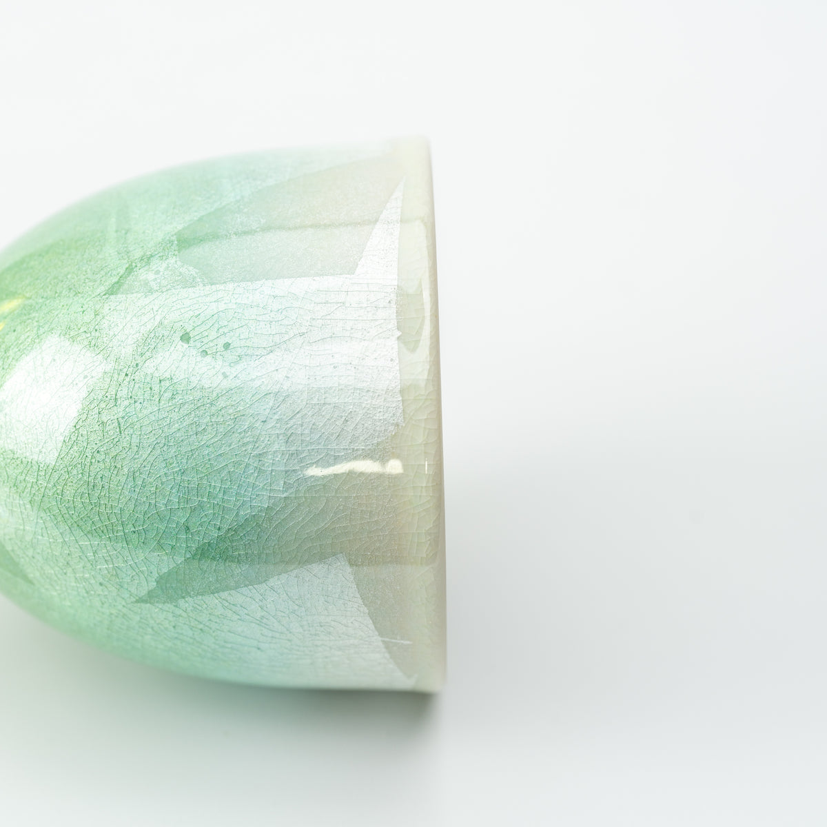 Close-up of the green Kutani wine cup's shimmering patchwork surface near the rim.