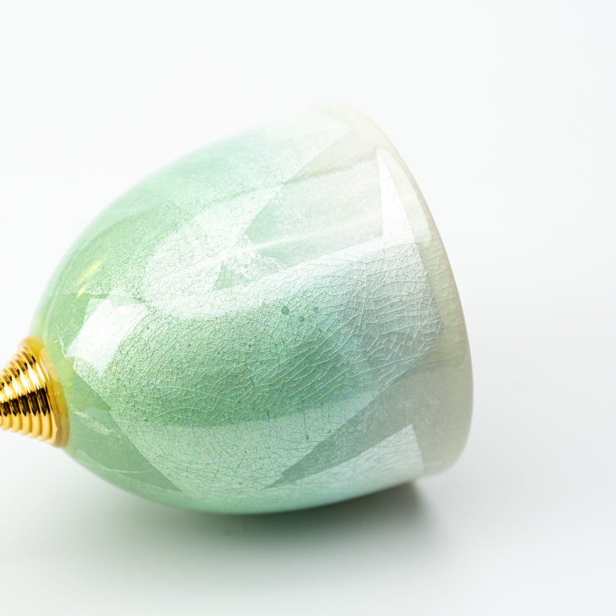 Side view of the pale green Kutani wine cup's rounded bowl and gold-colored stem connection.