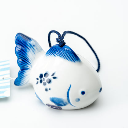 Three-quarter view of the goldfish wind chime, showing blue fins and a flower motif on its white body.