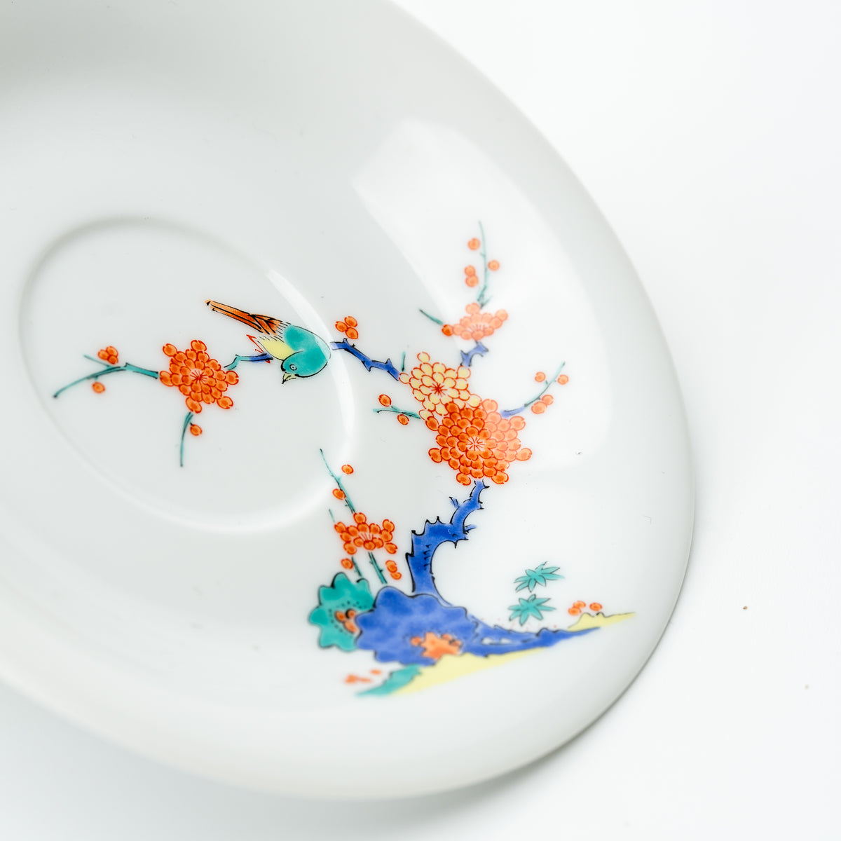 Close-up of the plum blossom saucer's turquoise bird, orange blossoms and blue trunk.
