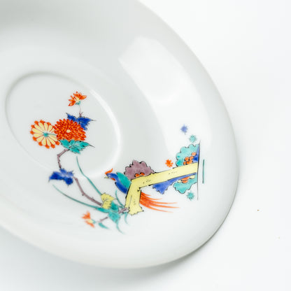 Detail of the white chrysanthemum and bird saucer with colorful flowers and a bird on a yellow branch.