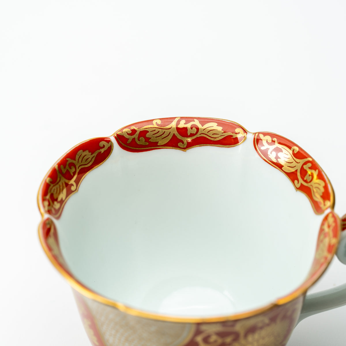 View inside the red-and-gold chrysanthemum cup, showing its pale interior and scalloped decorated rim.