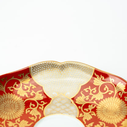 Detail of the red chrysanthemum saucer's scalloped edge and densely dotted gold-colored panel.