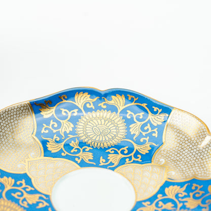 Close-up of the blue chrysanthemum saucer with gold-colored floral scrollwork and a scalloped rim.