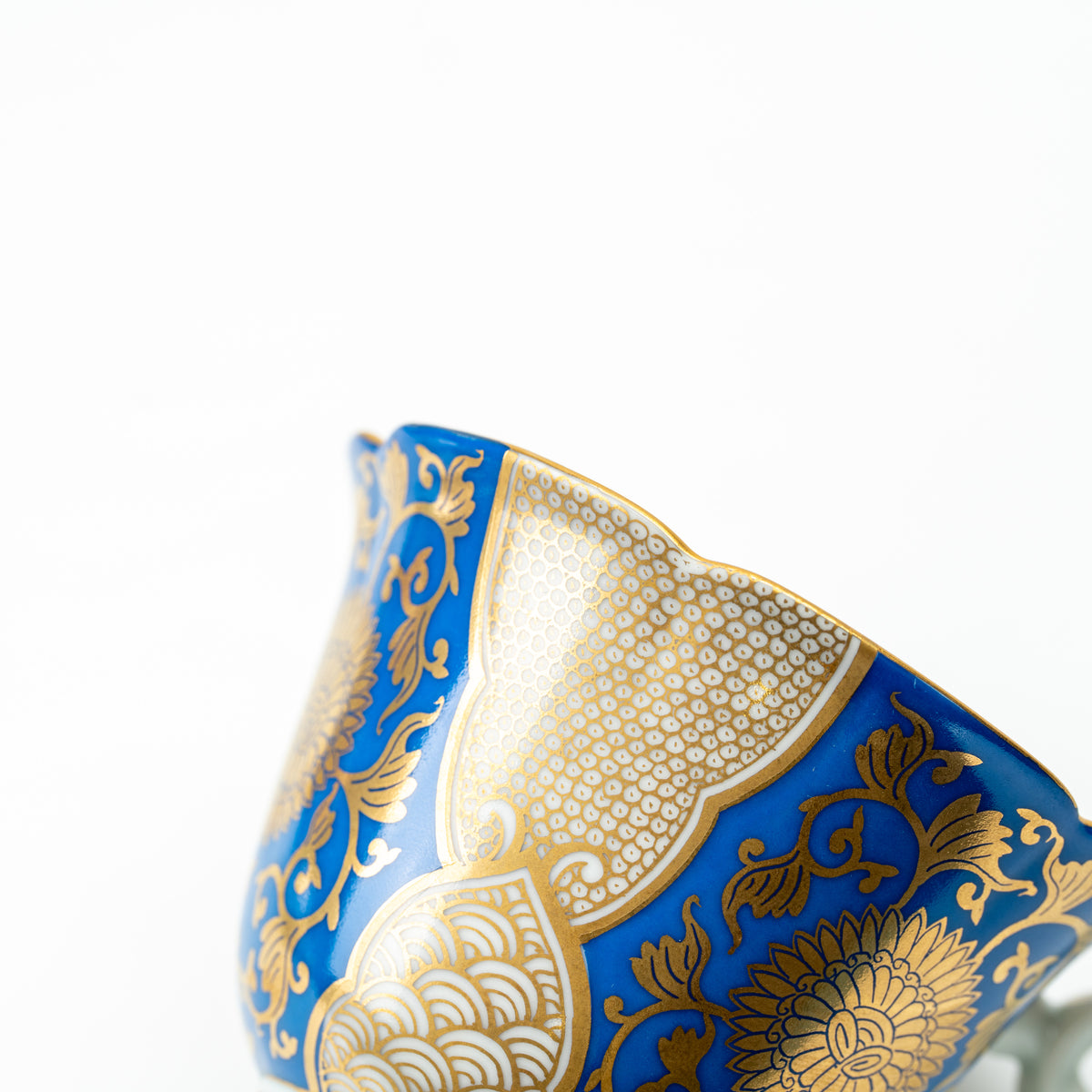 Detail of the blue chrysanthemum cup's flared side with gold-colored flowers and geometric panels.