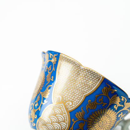 Detail of the blue chrysanthemum cup's flared side with gold-colored flowers and geometric panels.