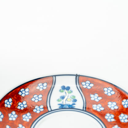 Close-up of the Four Gentlemen saucer's red floral border and a blue-and-green flower panel.