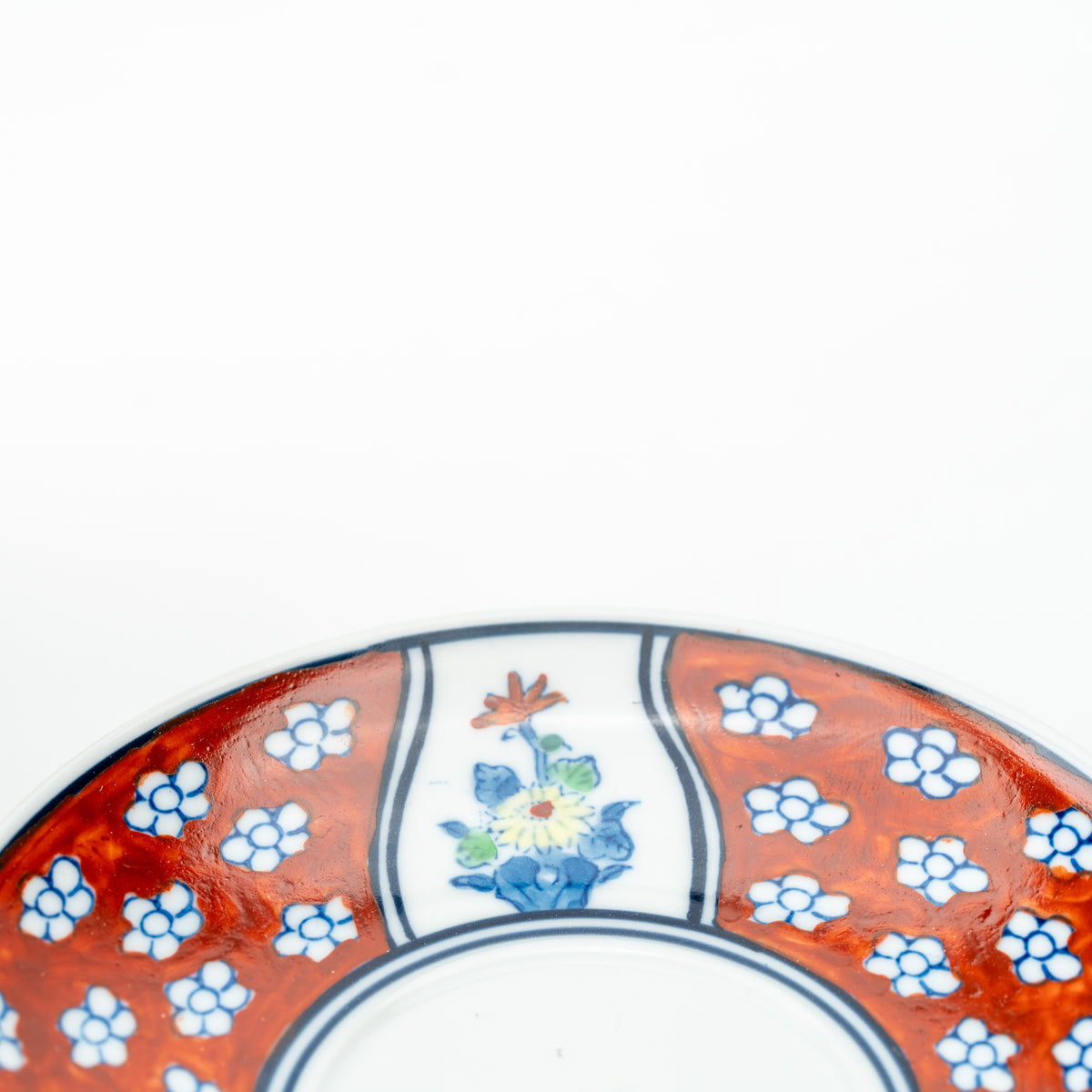 Close-up of a multicolored flower panel in the Four Gentlemen saucer's red-and-blue border.
