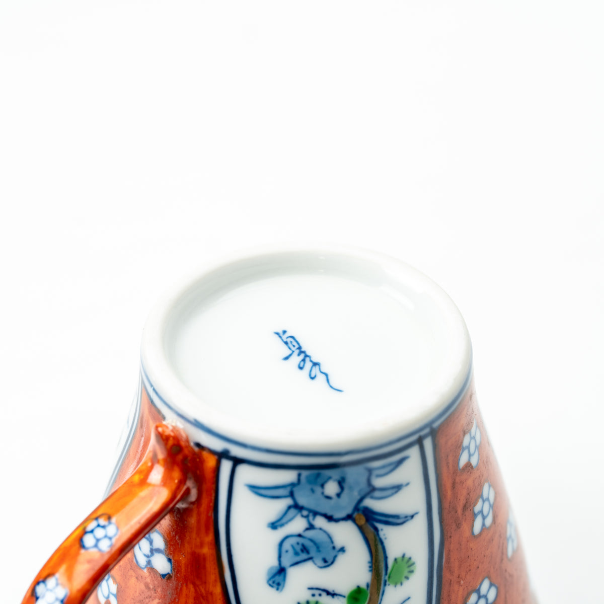 Underside of the Four Gentlemen cup, showing a blue maker's mark and floral decoration around the base.