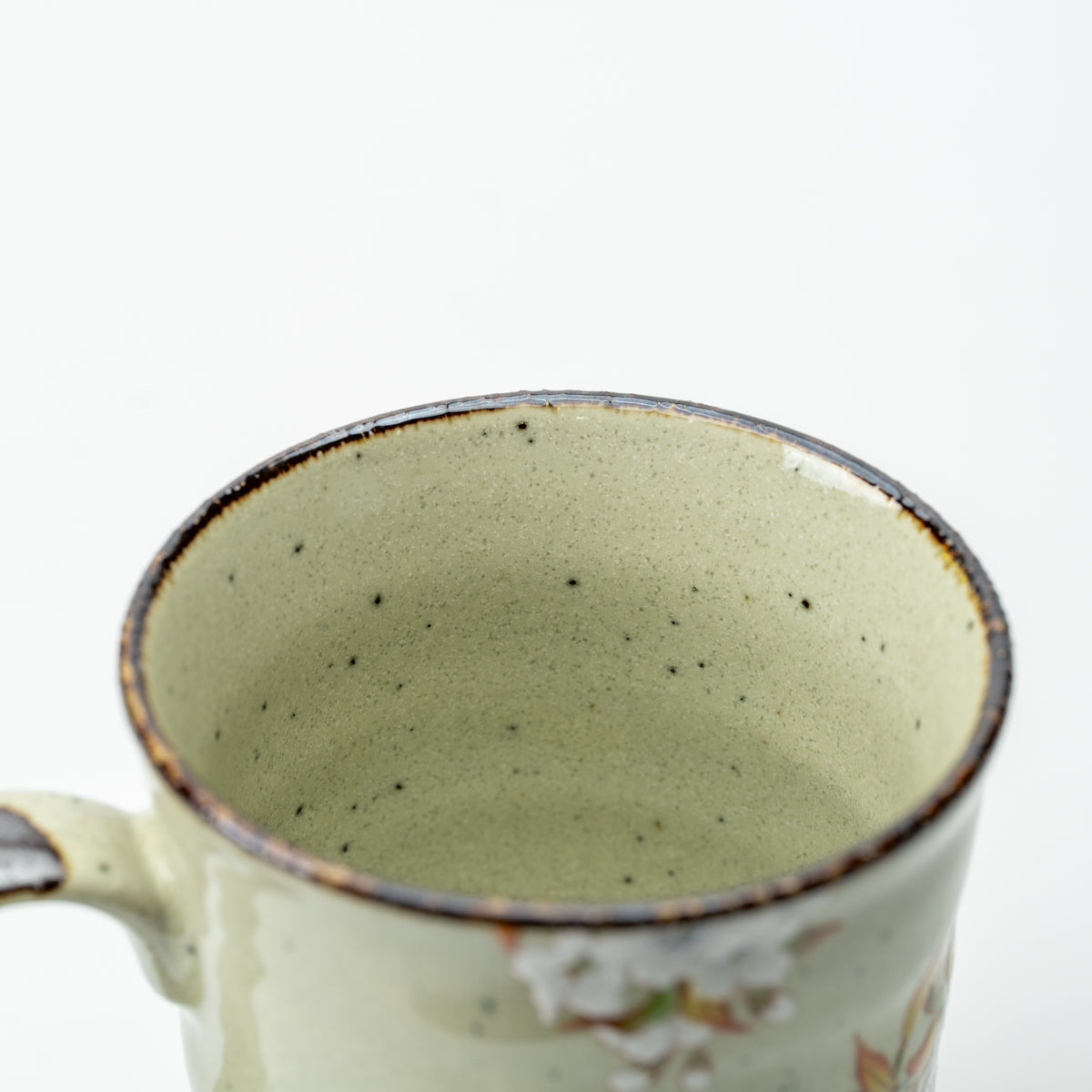 View into the Kutani bird mug, showing its speckled pale green interior and dark-edged rim.