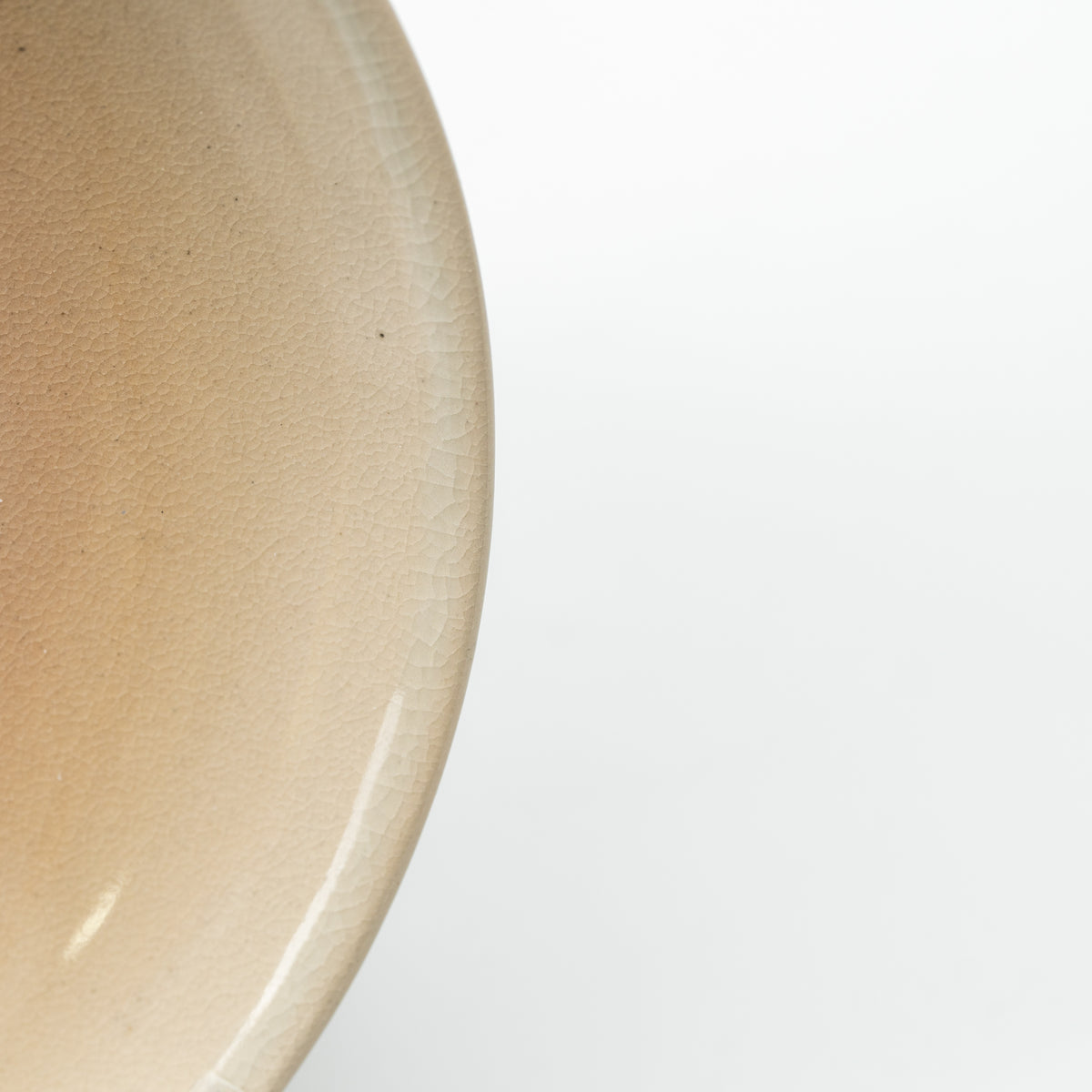 Detail of the Hagi Himetsuchi saucer's subtly speckled beige glaze and curved edge.